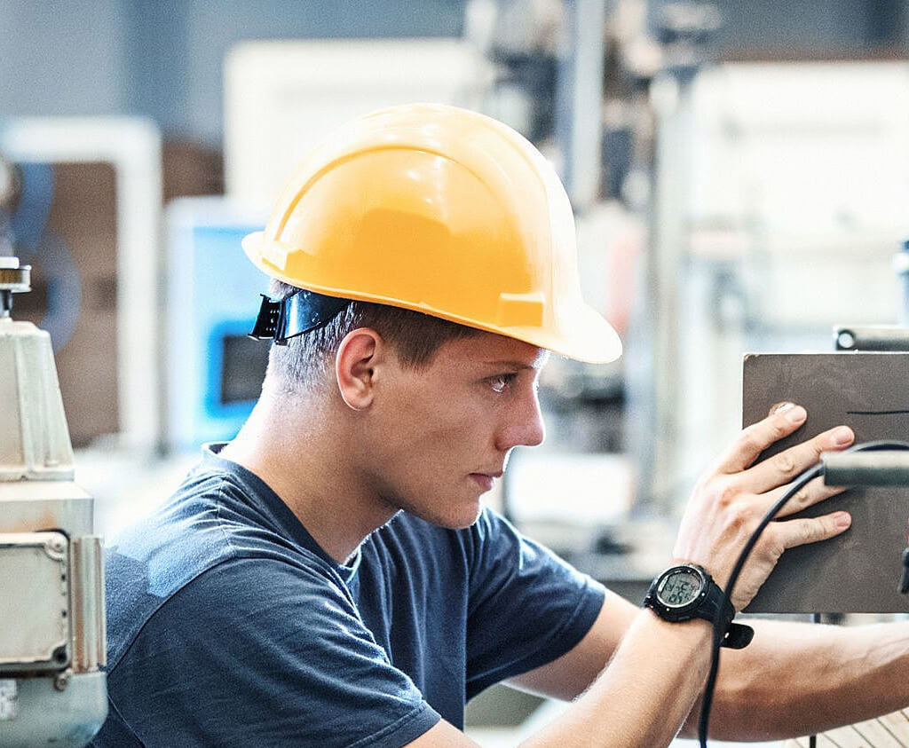 Technicien en train d’ajuster une machine automatisée dans une usine